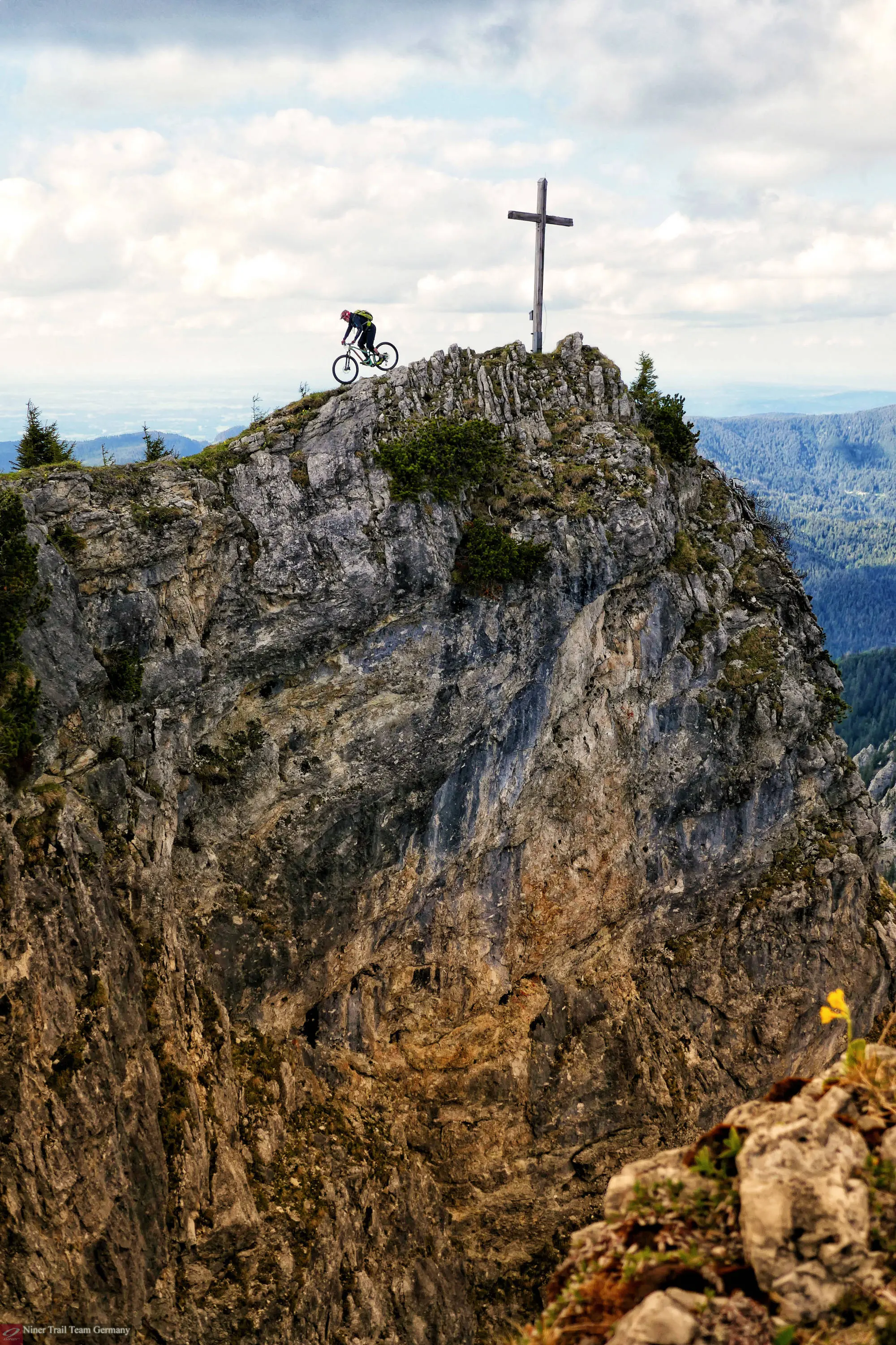 Gipfelkreuz mit Bike, Gratwanderung mit dem Bike am Abgrund.